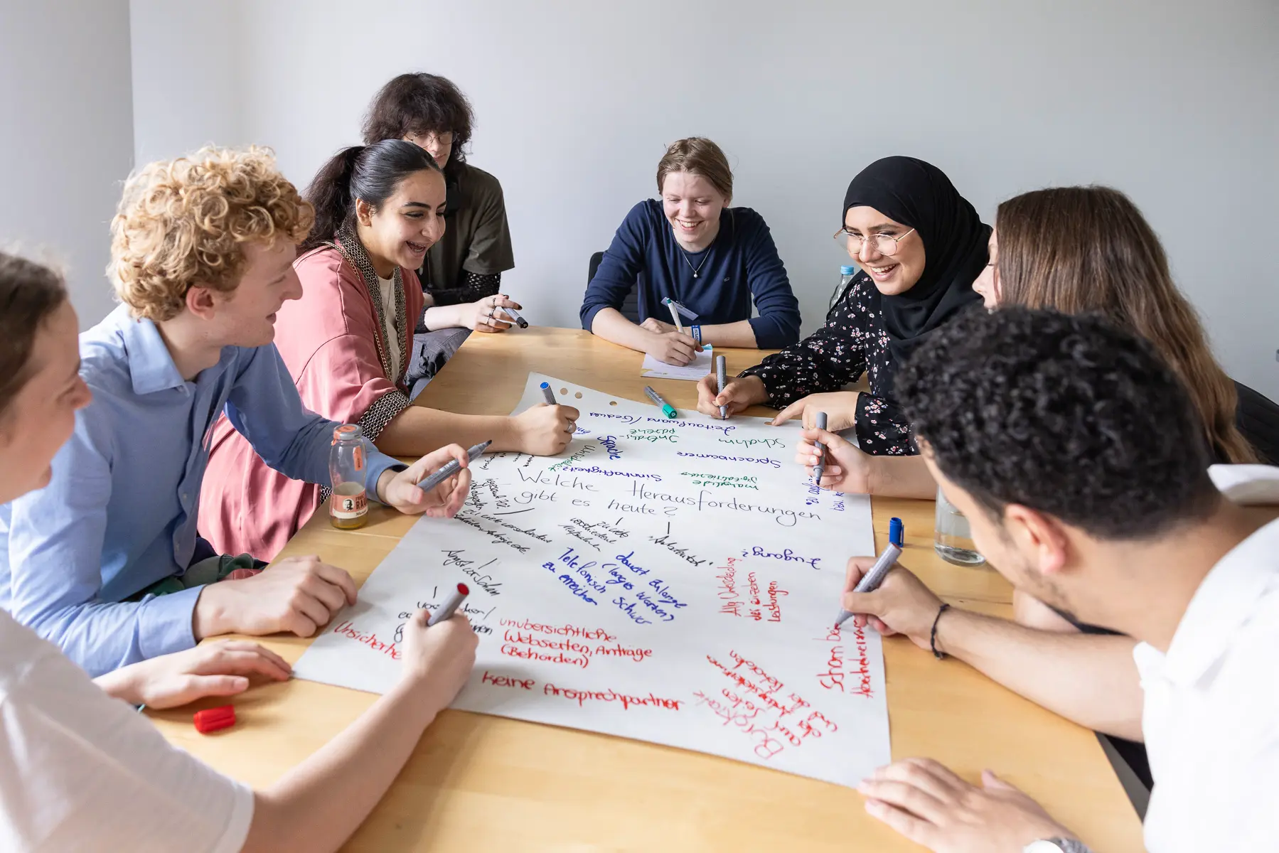 Junge Menschen sitzen im Rahmen eines Workshops um einen Tisch.