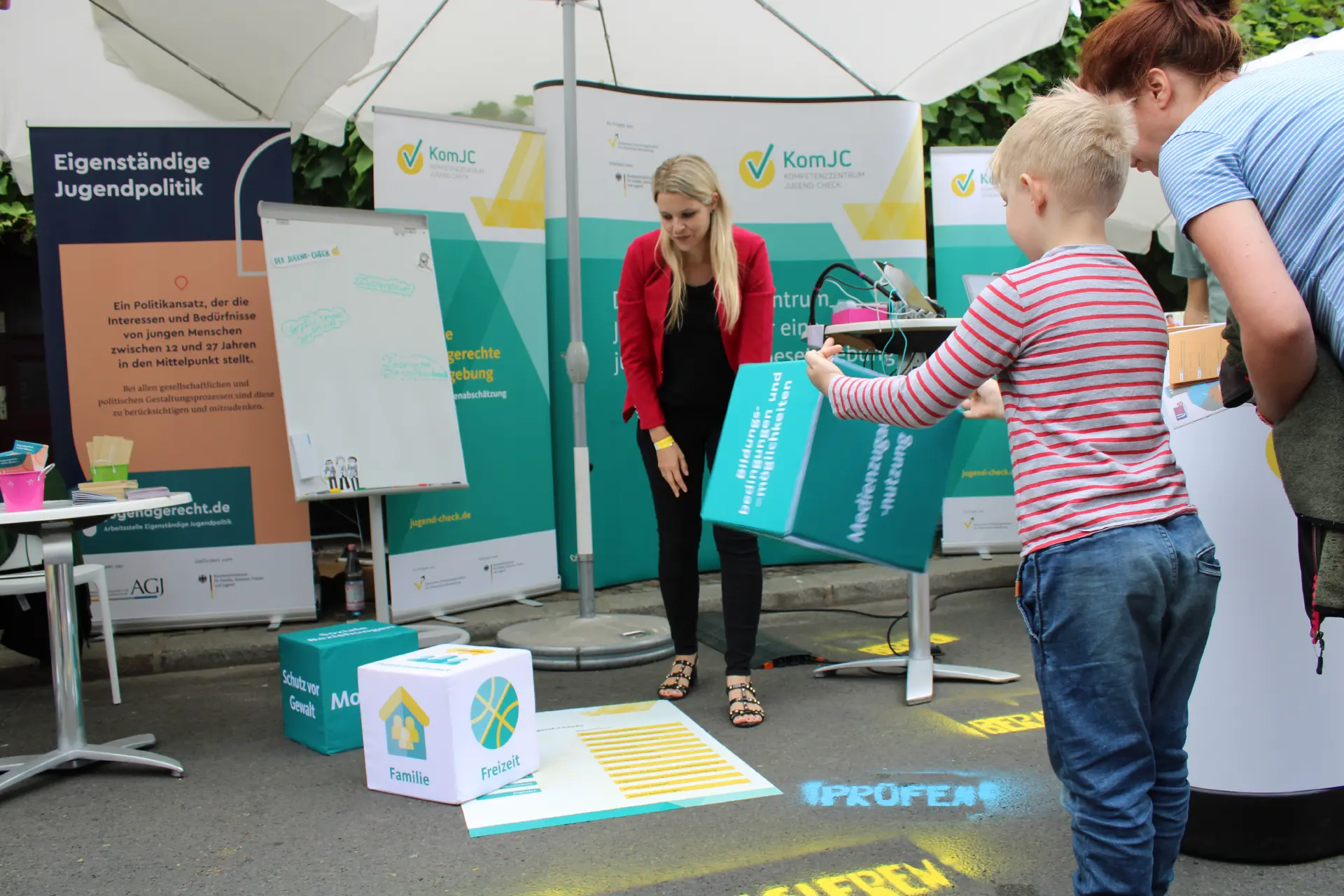 Ein Kind wirft an einem Stand des KomJC einen Würfel mit den aufgedruckten Wirkdimensionen.