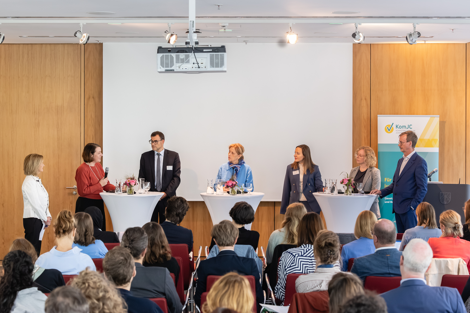Panel: Sieben Personen an Stehtischen.