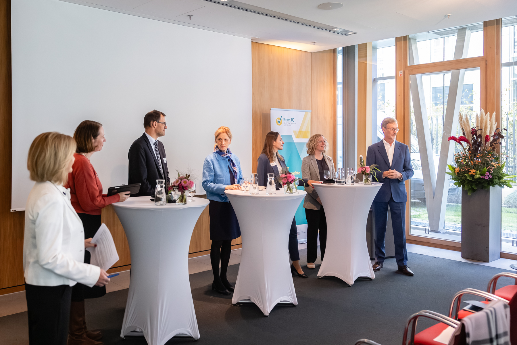 Aufnahme des vollständigen Panels, sieben Personen an Stehtischen.