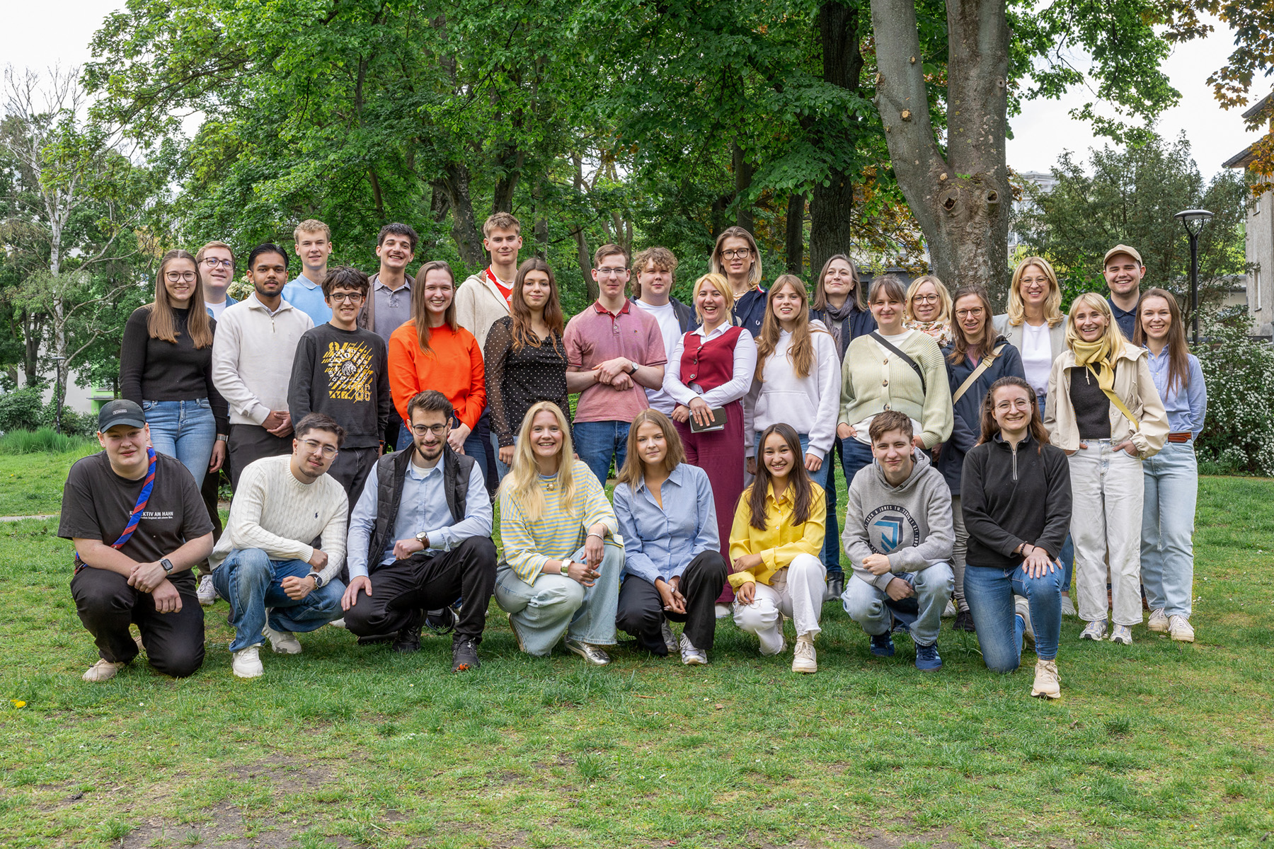 Gruppenbild des Beteiligungsworkshops. Circa 35 Menschen stehen vor einem grünen Hintergrund.