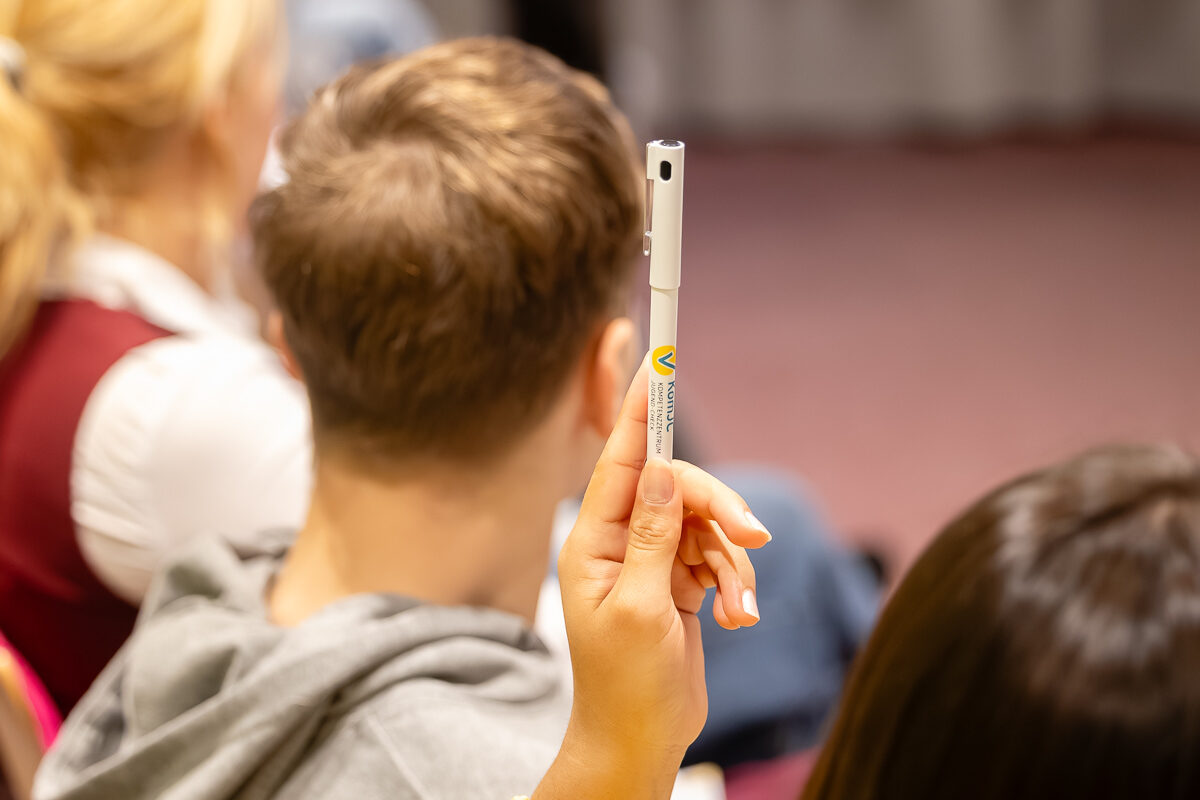 Eine Teilnehmerin meldet sich mit einem Stift in der Hand.